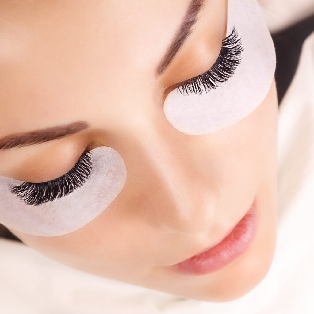 Eyelash Extension Procedure. Woman Eye with Long Eyelashes. Close up, selective focus